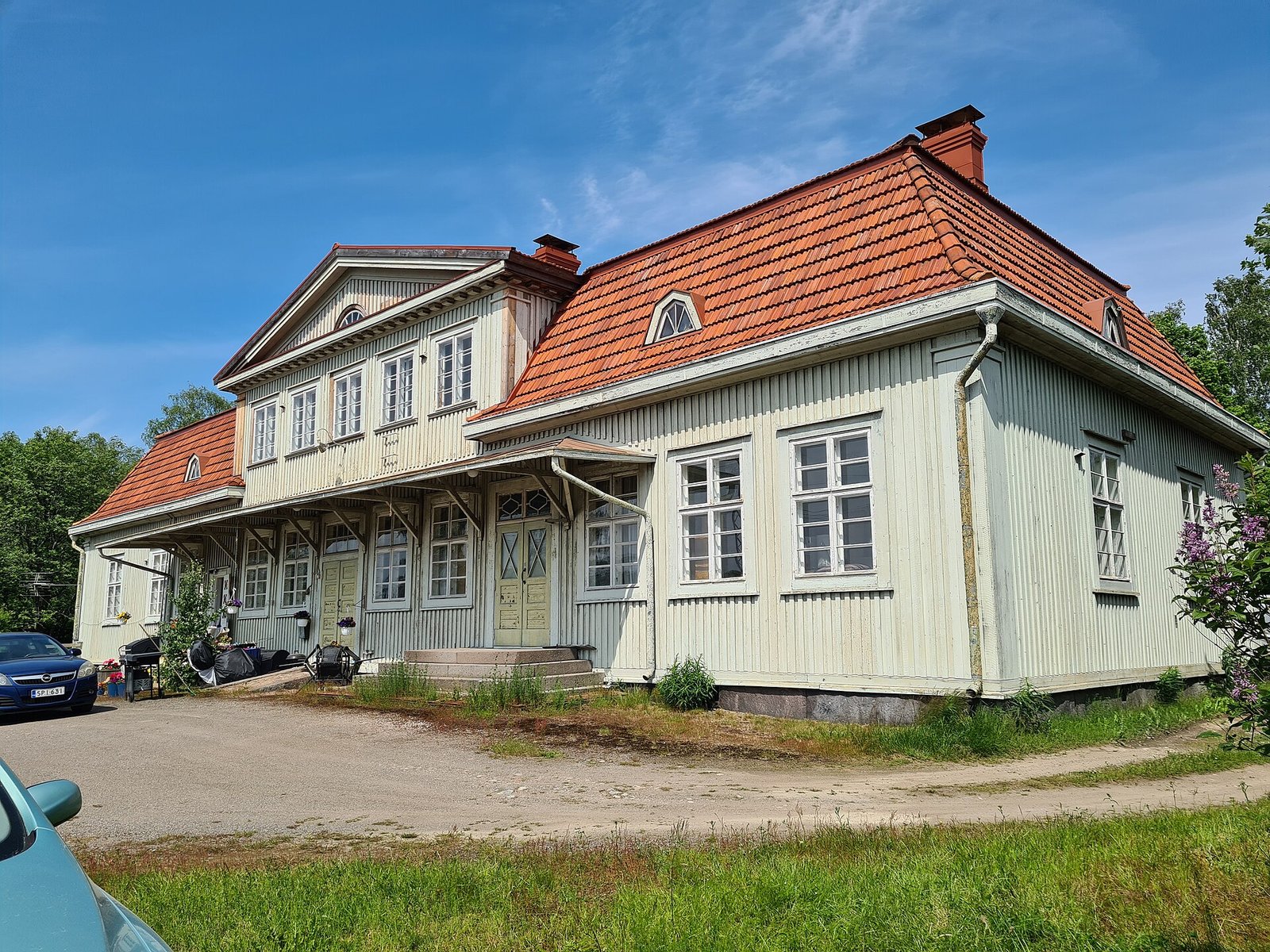 Vaaleaksi maalattu puinen rautatieasemarakennus Raision radan varressa