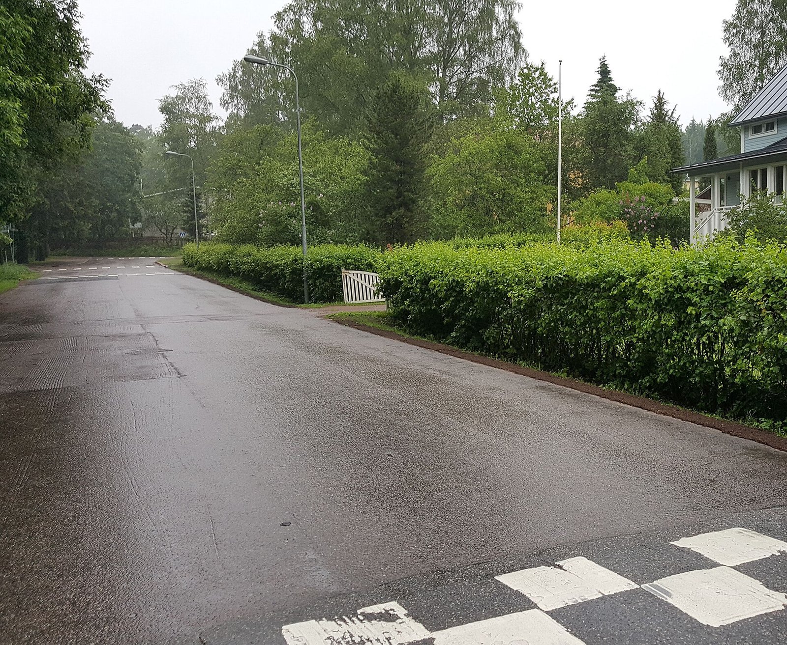 Asfalttitie, pensasaita ja omakotitalo Marttilan keskustassa