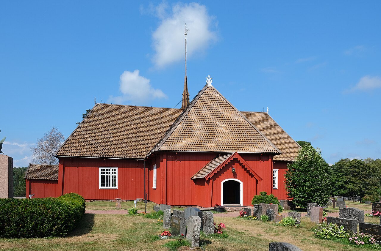 Punainen puukirkko, jossa on korkea paanukatto ja kellotorni