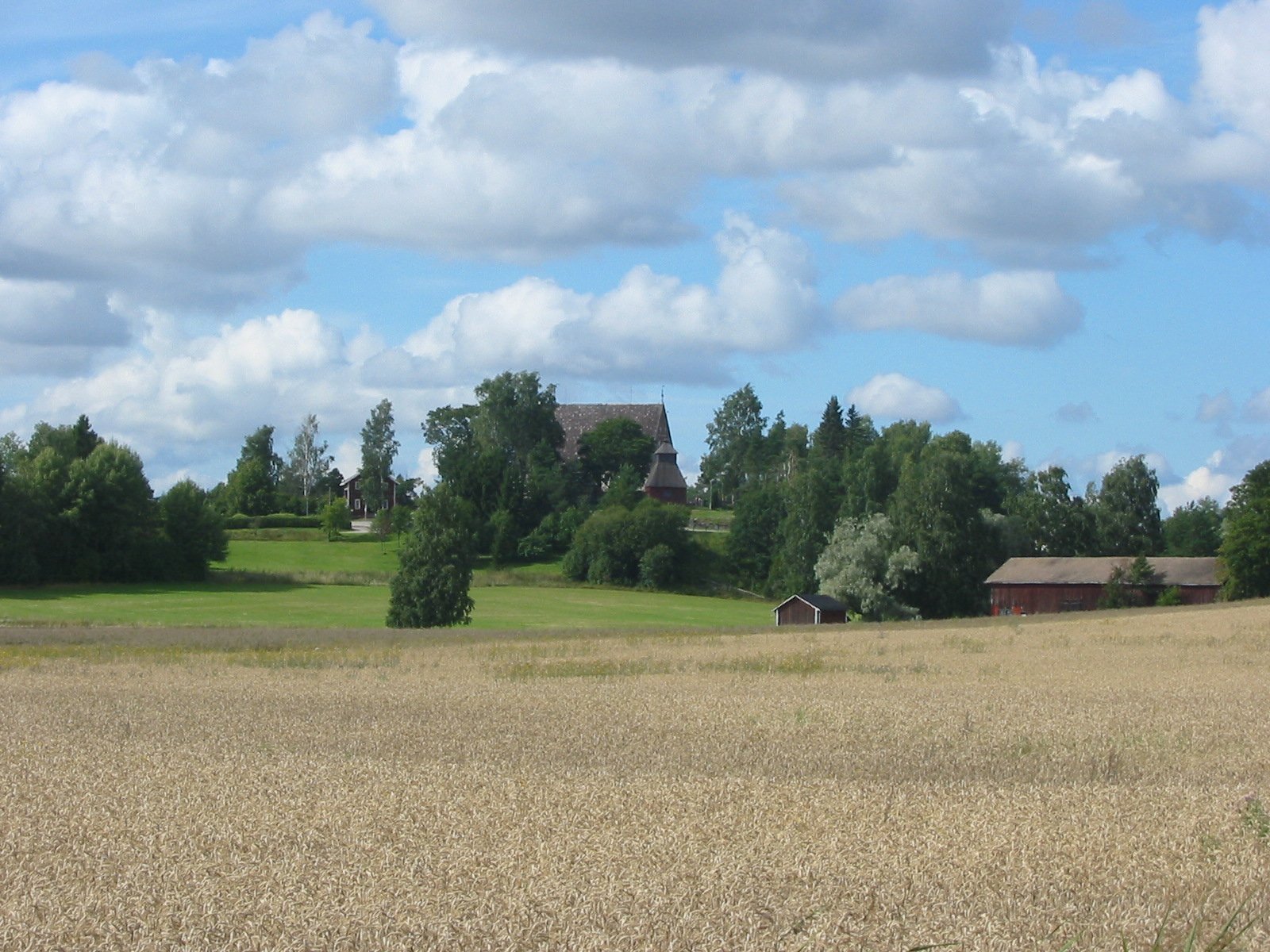 Ruskon kirkonkylä peltojen takaa, kirkko mäellä