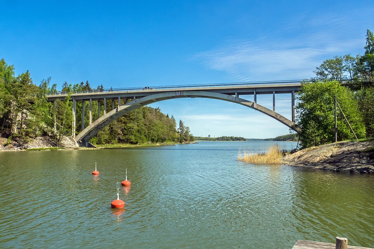 Betooninen kaarisilta joen yllä, rannoilla metsää