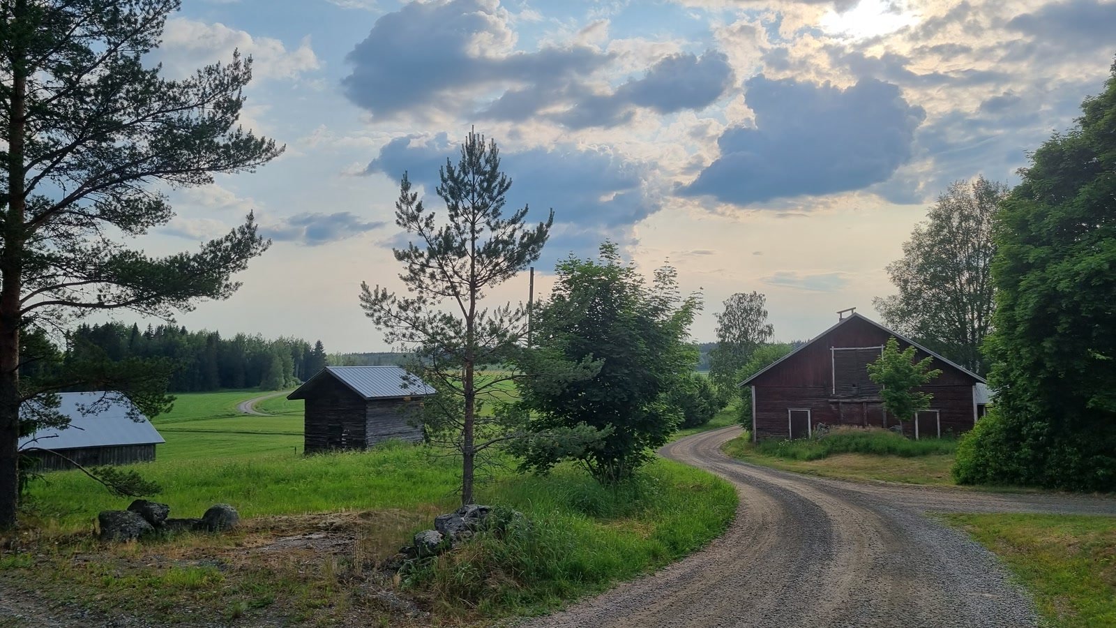 Torron kylän soratietä ja punaisia maatalousrakennuksia